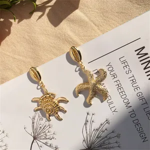 Detailansicht goldener Ohrringe mit Seestern- und Schildkrötendesign im Meerestil