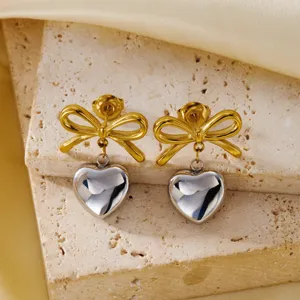 Close-up detail of vintage style stainless steel bow and heart drop earrings on stone