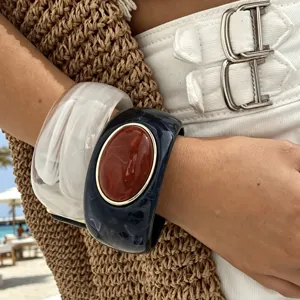 Primo piano dettagliato di bracciali rigidi in resina con finta agata per look da spiaggia.