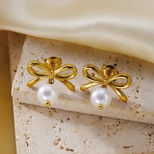 Detail view of elegant gold bow earrings with white pearl drops on stone