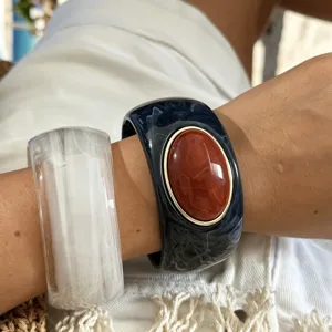 Dettaglio di ampi bracciali rigidi in resina marmorizzata con finta agata per vacanza.