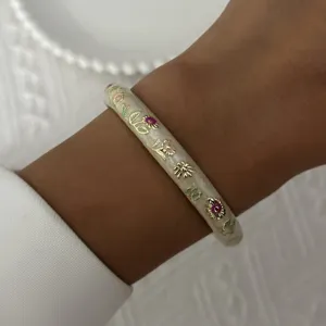 Close-up of a vintage enamel bracelet with colorful floral patterns on a woman's wrist