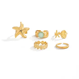 Gouden teenringen set in oceaanthema met zeesterren, schelpen en groene steeninleg