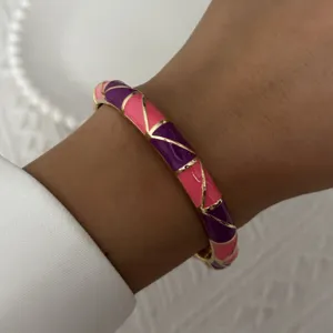 Detailed macro shot of a vintage pink and purple enamel bangle with elegant gold trim detail