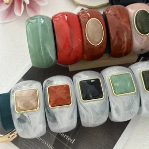 Vista dettagliata di bracciali rigidi effetto agata con inserti metallici geometrici.