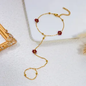 Elegante bracciale anello a catena dorata con perline a fiore rosse e oro.