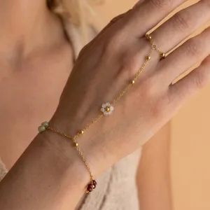 Vista dettagliata di un bracciale a catena per mano dorato con ciondoli a fiore.