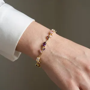 Elegant gold-plated vine bracelet with colorful gemstones worn on a wrist detail