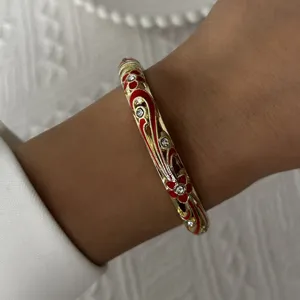 Vintage gold-plated enamel bangle with intricate red floral patterns and crystal accents