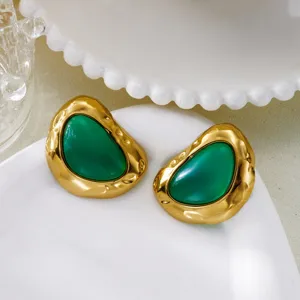 Detail view of vintage gold hammered earrings with large translucent green stones.