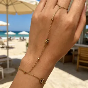 Bracciale ad anello in oro con perline delicate indossato su una mano al mare