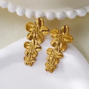 Close-up macro shot of vintage gold stainless steel triple flower drop earrings texture