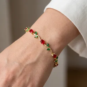Elegant gold-plated vine bracelet featuring red and green crystal leaf details on wrist