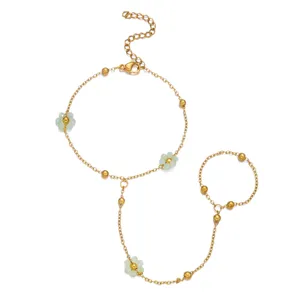 Vista dettagliata di un bracciale anello dorato con delicati ciondoli a fiore e perline