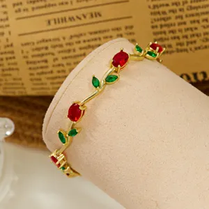 Detailed macro view of a gold-plated vine bracelet featuring red and green crystals
