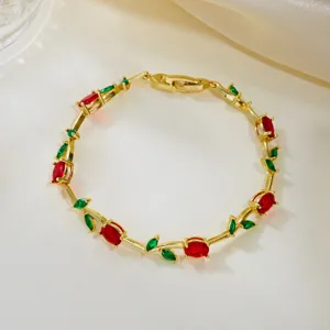 Close-up of elegant gold vine bracelet with red and green crystal gemstones.