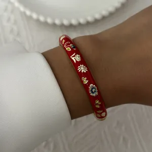 Detailed close-up view of a vintage red enamel floral bangle bracelet worn on a wrist