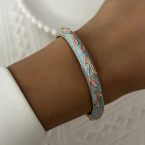 Close-up detail of an elegant vintage light blue enamel bangle with pink floral pattern