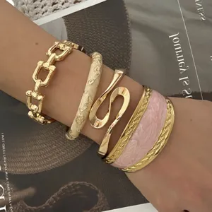Detailed close-up of a layered gold-tone bracelet set with pink enamel and chain links