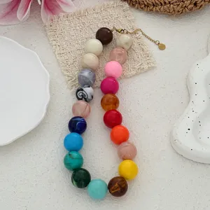 Vue détaillée d'un tour de cou bohème à grosses perles colorées sur fond en lin