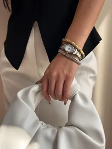 Elegant detail shot showing silver steel watch paired with rhinestone bracelets on a wrist