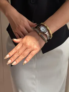Close-up detail of a silver hexagonal watch paired with crystal-set elastic bracelets on wrist