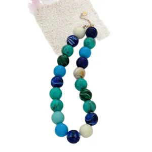 Collier bohème avec grosses perles marbrées multicolores sur fond blanc texturé
