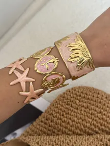 Detailaufnahme von rosafarbenen Emaille-Seestern- und Sonnenblumen-Armbändern aus Edelstahl