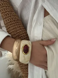 Détail d'un bracelet en résine bohème avec pierre rouge et jonc doré chic et épais