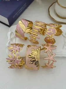 Detail von rosa-goldenen Edelstahl-Armreifen mit Seestern- und Sonnenblumenmotiven