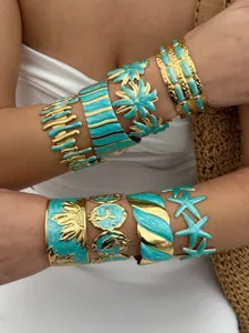 Detailed view of multiple gold and turquoise enamel cuff bracelets with summer motifs.
