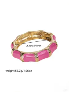Close-up of a hot pink enamel bangle with gold finish, showing length and weight details