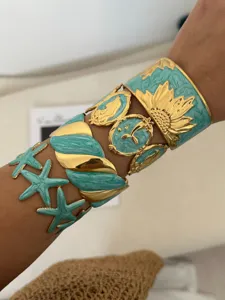 Detail of turquoise enamel and gold plated stainless steel bangles with sunflower design