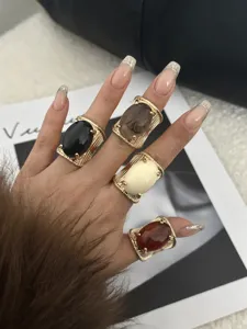 Detailed view of four chunky gold-tone rings featuring large colorful resin stones.