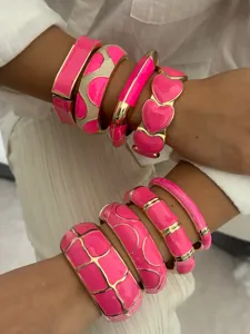 Detailed view of vibrant pink enamel bangles with luxurious gold-toned metal frames