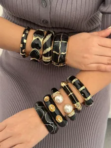 Gedetailleerde weergave van zwarte emaille en goudkleurige armbanden set