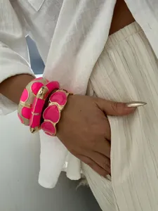 Close-up view of vibrant rose pink enamel dopamine bangles worn on a model's wrist