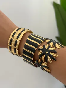 Detailansicht von stapelbaren Gold- und Schwarzemaille-Armreifen am Handgelenk