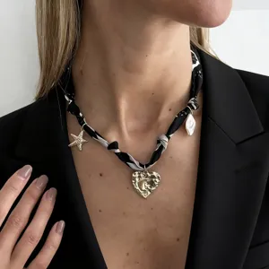 Detail shot of retro silk scarf necklace featuring golden lava heart and starfish charms