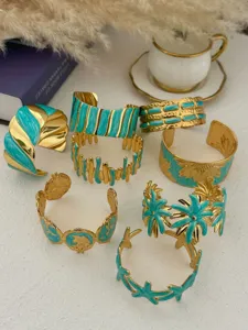 Variety of gold stainless steel cuff bracelets with turquoise enamel floral patterns.