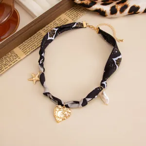 Close-up of a vintage scarf choker with gold lava heart and pearl charms jewelry