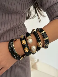 Gedetailleerd overzicht van luxe gestapelde zwarte emaille armbanden met gouden accenten.
