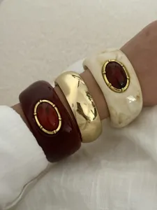 Detaillierte Nahaufnahme von Vintage-Resin- und Goldarmreifen mit roten Kunststein-Inlays