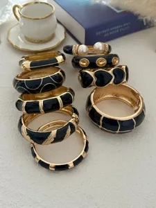 Gedetailleerd overzicht van vintage zwarte emaille en goudkleurige stapelbare armbanden