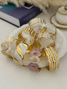 Makro-Detail von verschiedenen Edelstahl-Armreifen in Gold und weißem Emaille