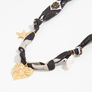 Close-up detail of Maillard leopard scarf necklace with gold heart and pearl charms.