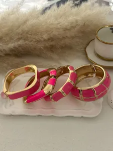 Detailed view of luxury rose pink fuchsia enamel gold-toned cuff bracelets set