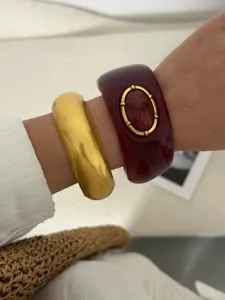 Détail de gros bracelets en résine dorée et bordeaux de style bohème ethnique