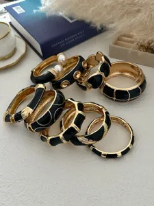 Detailweergave van vintage zwart emaille en goudkleurige armbanden met parels en golven