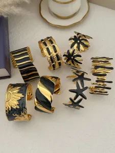 Kollektion von gold-schwarzen Emaille-Edelstahl-Manschettenarmbändern mit Mustern